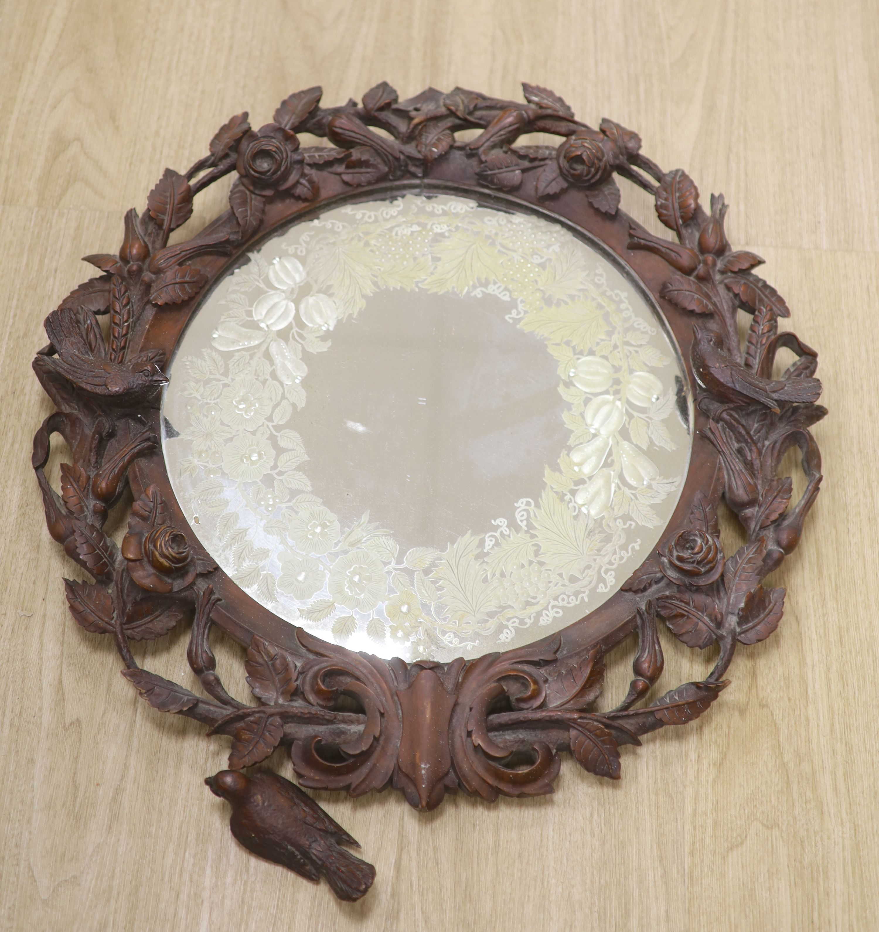 A Black Forest walnut wall mirror carved with roses, diameter 56cm